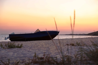 Photo of Beautiful view of beach with boat at sunset