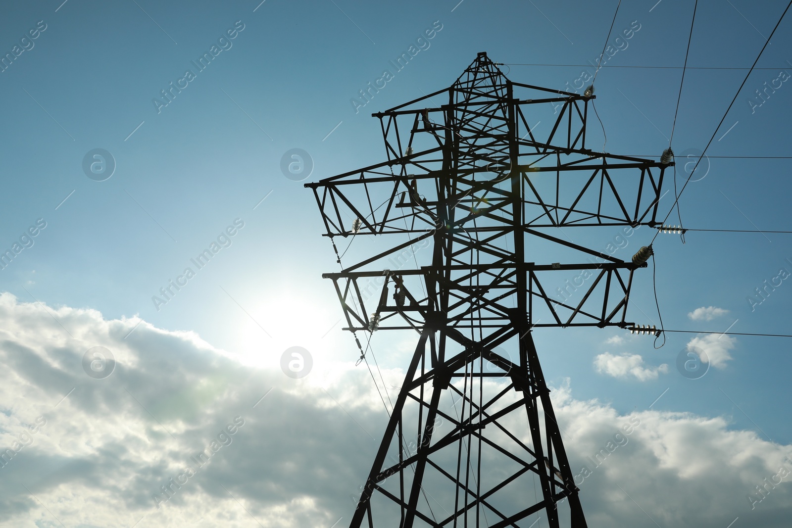 Photo of Telephone pole and wires against blue sky with clouds