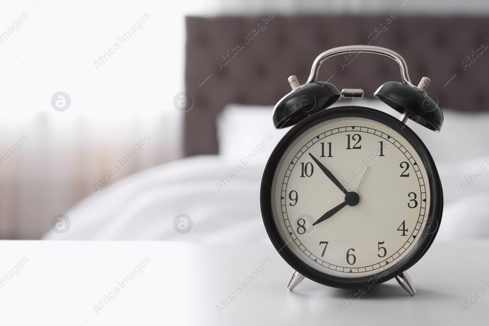 Photo of Alarm clock on table in bedroom. Time to wake up