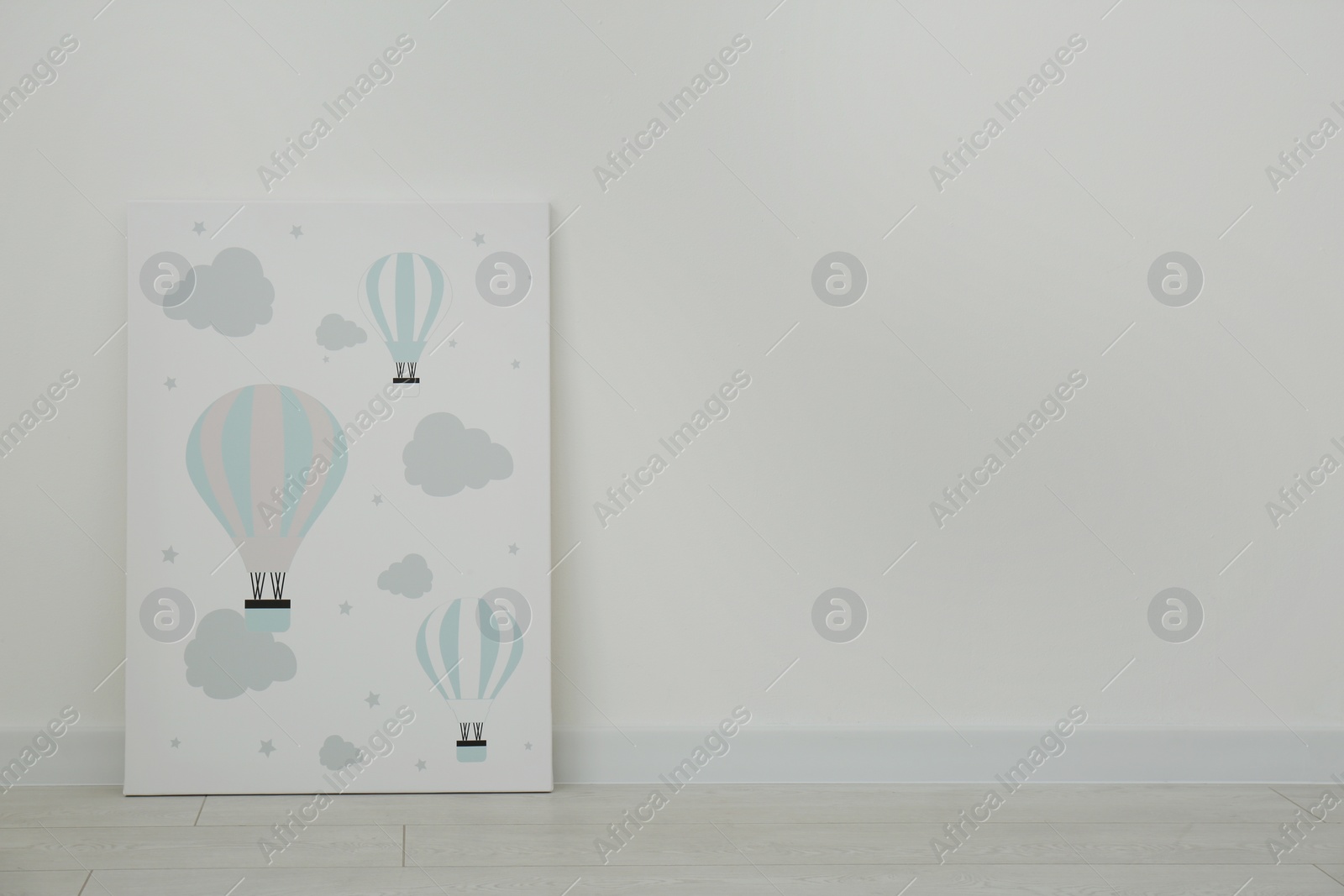 Photo of Adorable picture of air balloons on floor near white wall, space for text. Children's room interior element