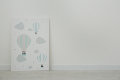 Photo of Adorable picture of air balloons on floor near white wall, space for text. Children's room interior element