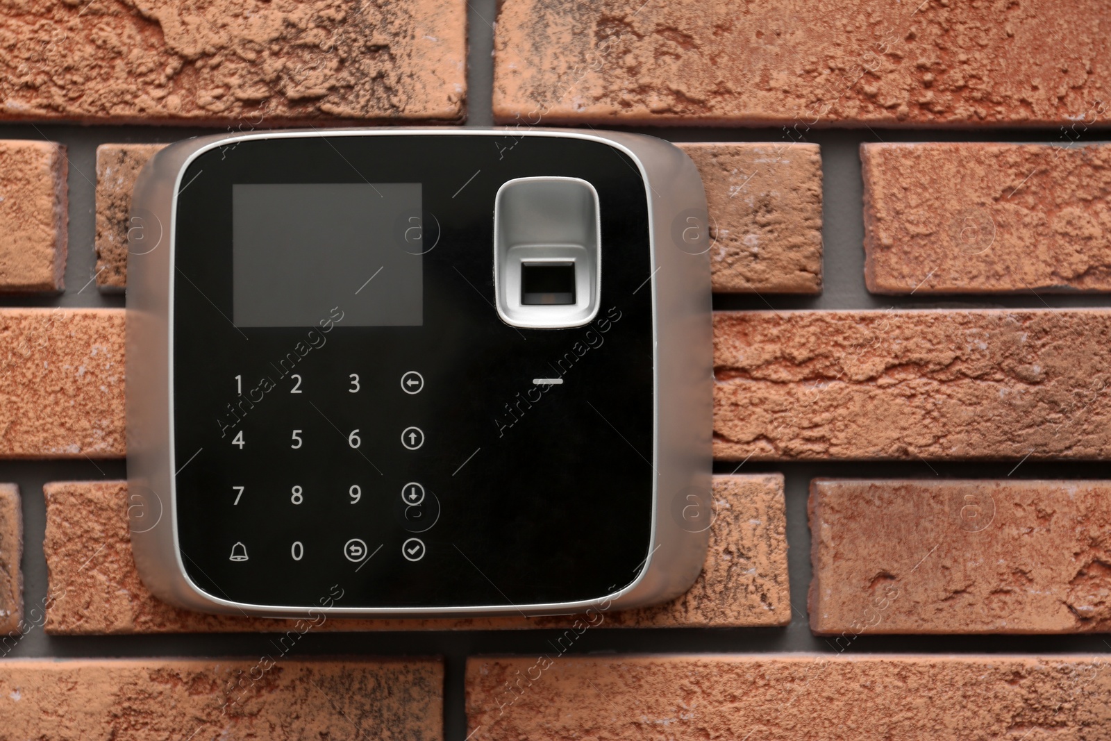 Photo of Modern alarm system with fingerprint scanner on brick wall. Space for text