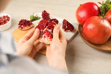 Woman with delicious ripe pomegranate at wooden table, closeup