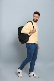 Photo of Young man with stylish backpack walking on light grey background