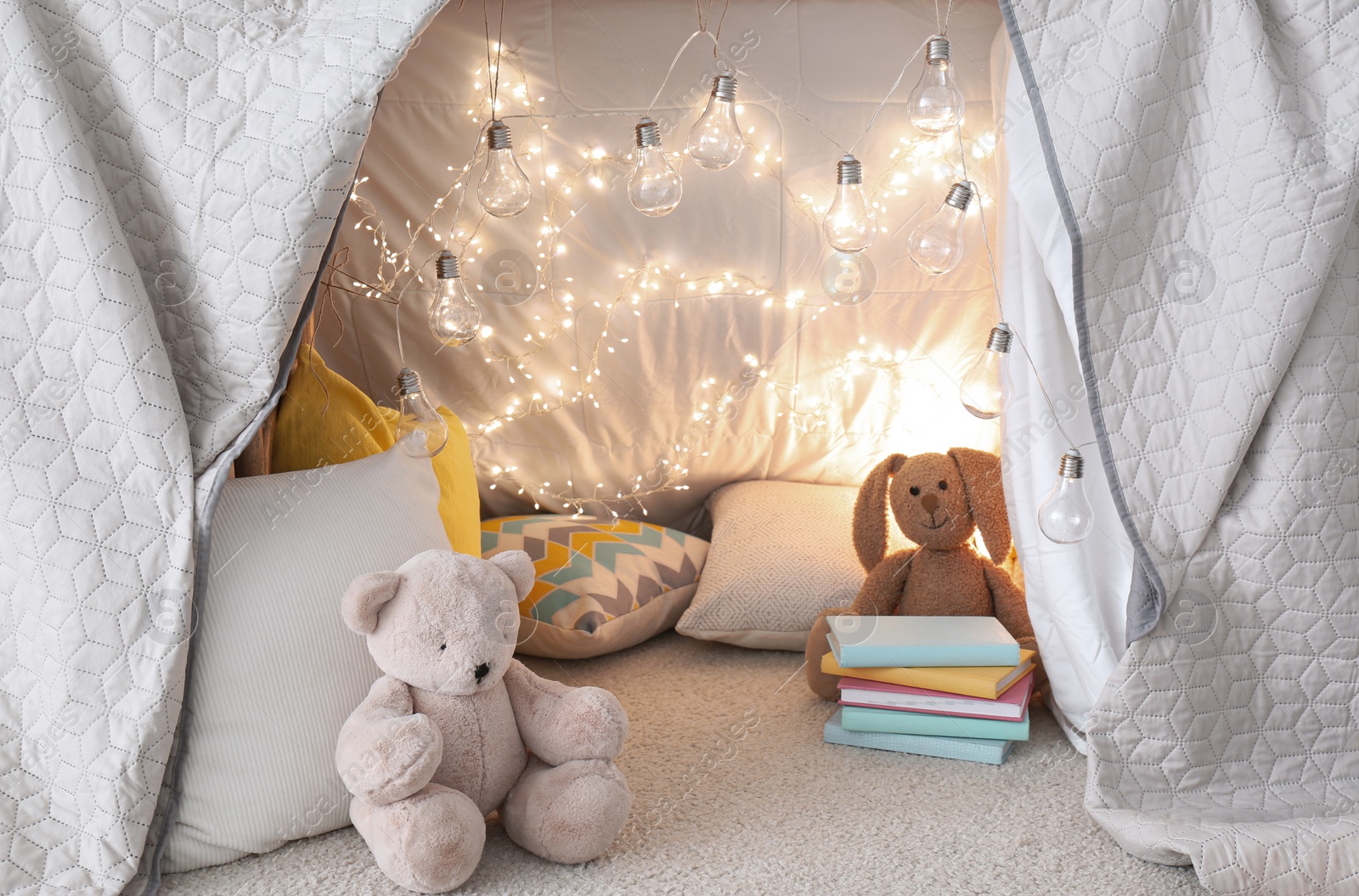 Photo of Play tent with toys and pillows indoors, closeup. Modern children's room interior