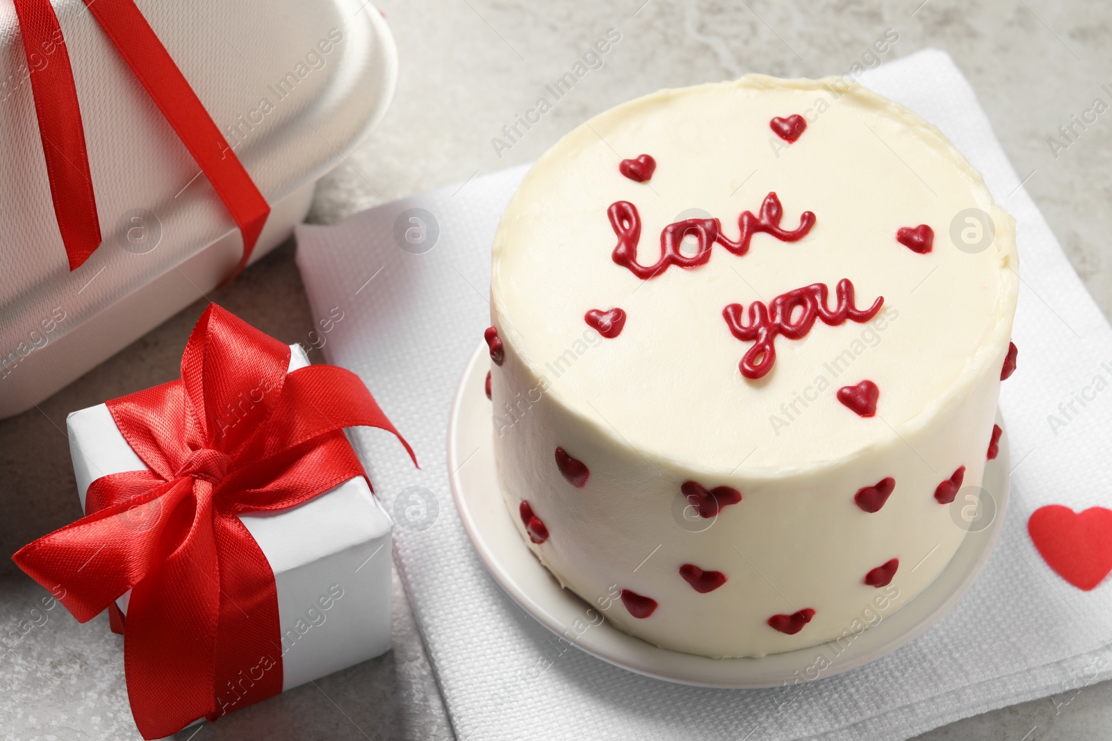 Photo of Bento cake with text Love You, takeaway packaging and gift box on grey table, closeup. St. Valentine's day surprise