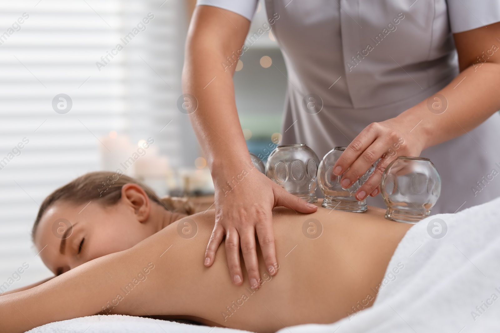 Photo of Therapist giving cupping treatment to patient in spa salon