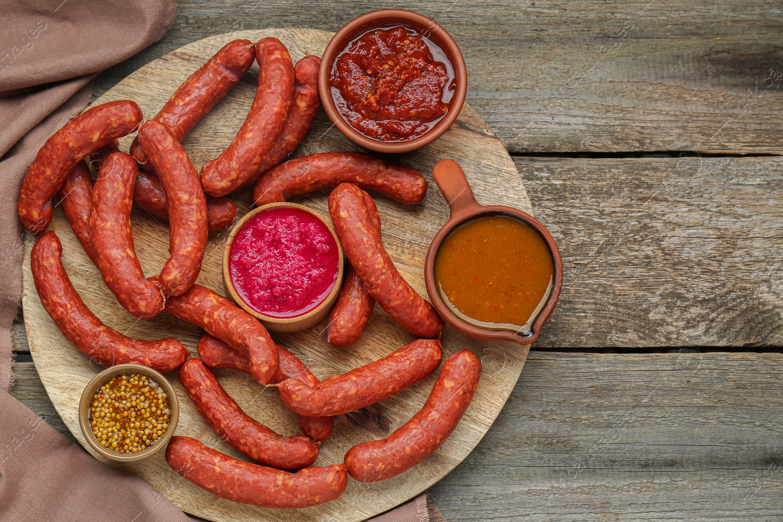 Photo of Delicious sausages, ketchup, mustard and horseradish on wooden table, top view. Space for text