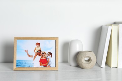 Photo of Frame with family photo, books and decor elements on white wooden table