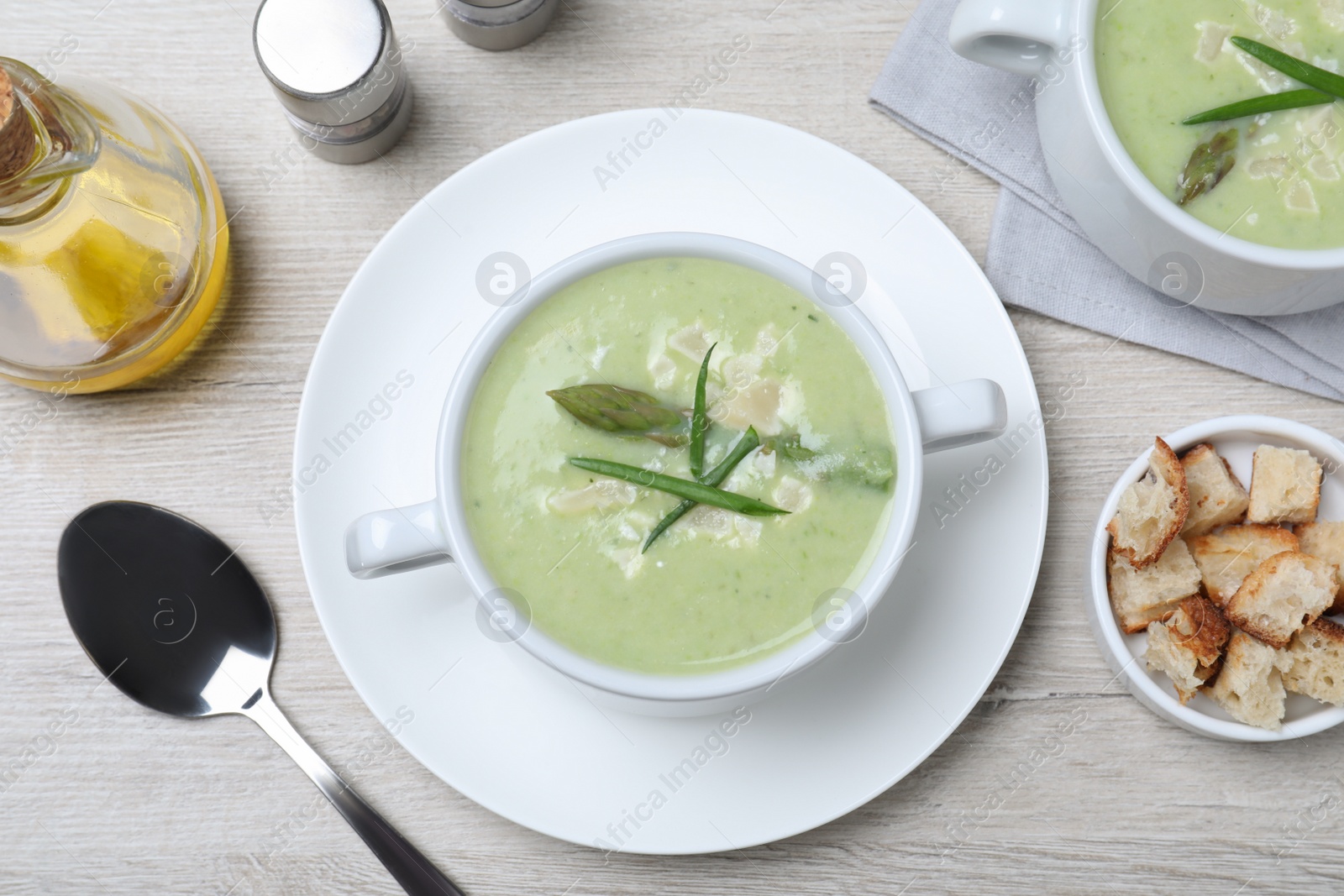 Photo of Delicious asparagus soup with green onion served on white wooden table, flat lay