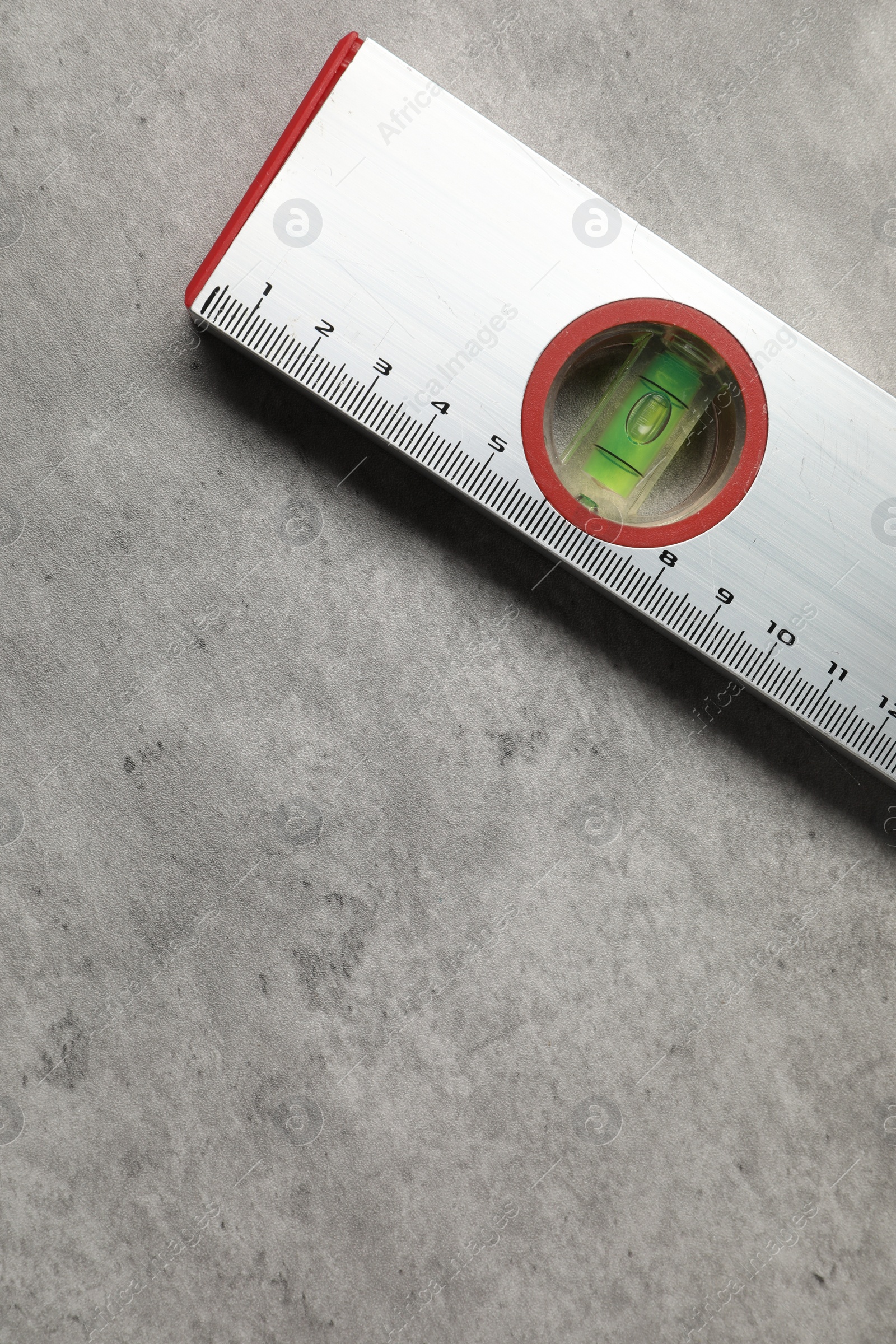 Photo of Aluminium building level on grey table, top view. Space for text