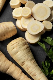 Photo of Whole and cut parsnips on wooden board, above view