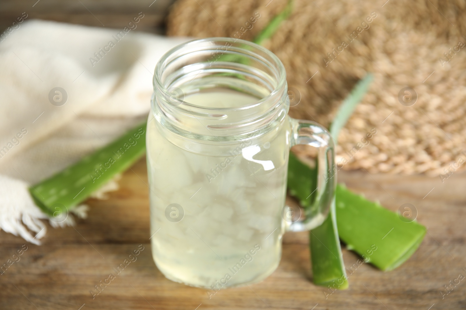 Photo of Fresh aloe drink in mason jar and leaves on wooden table