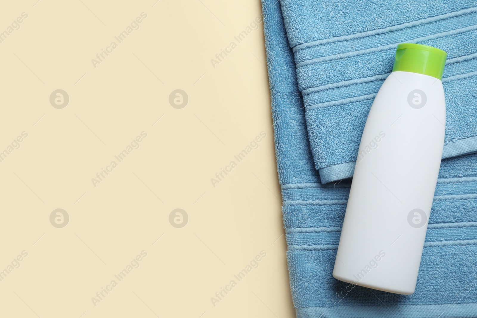 Photo of Bottle of shampoo and towel on color background, top view with space for text