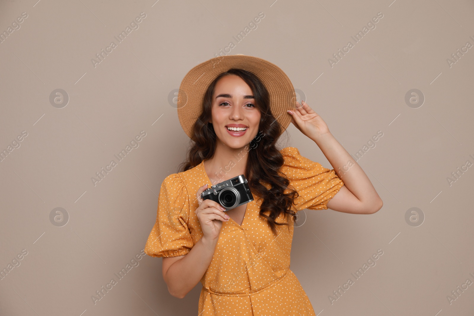 Photo of Beautiful young woman with straw hat and camera on beige background