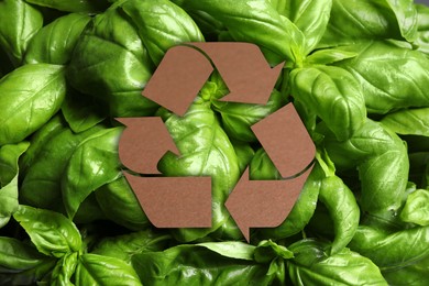 Image of Recycling symbol cut out of kraft paper and fresh green leaves on background