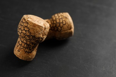 Photo of Sparkling wine corks with grape images on black table, closeup. Space for text