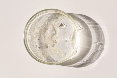 Photo of Petri dish with liquid sample on light background, top view