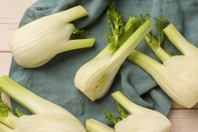 Photo of Whole and cut fennel bulbs on light wooden table, flat lay