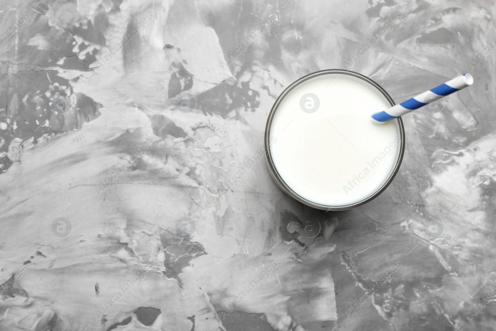 Photo of Glass of milk with straw on grey background, top view