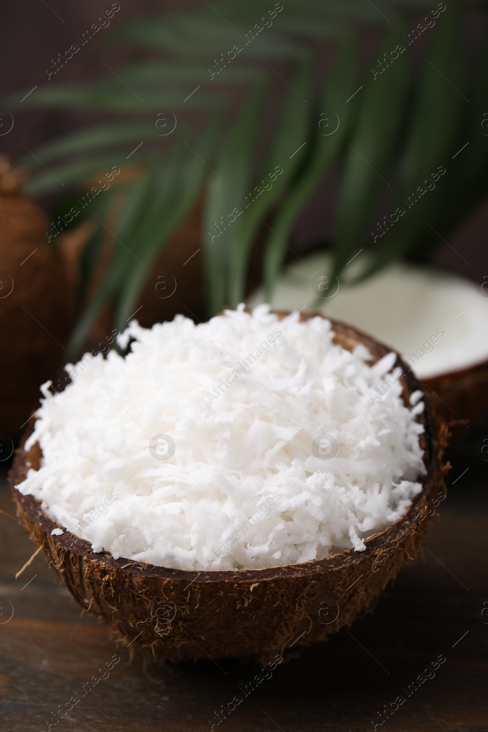 Photo of Coconut flakes in nut shell on wooden table