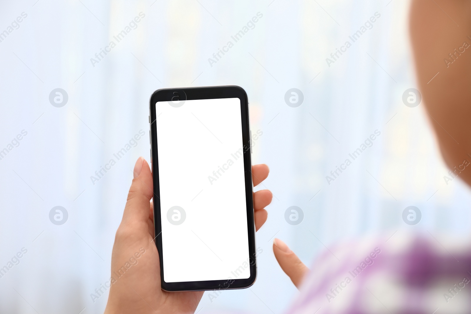 Photo of Woman holding smartphone with blank screen on blurred background, closeup of hands. Space for text