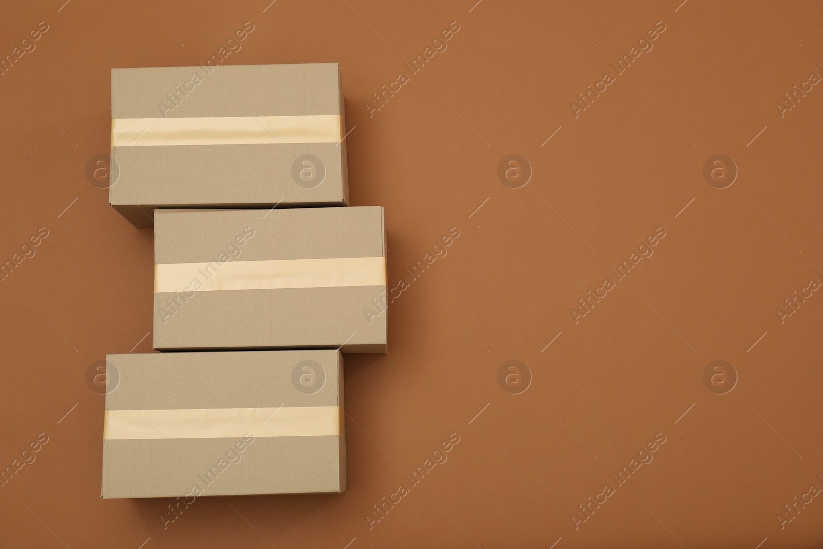 Photo of Cardboard boxes on brown background, flat lay. Space for text