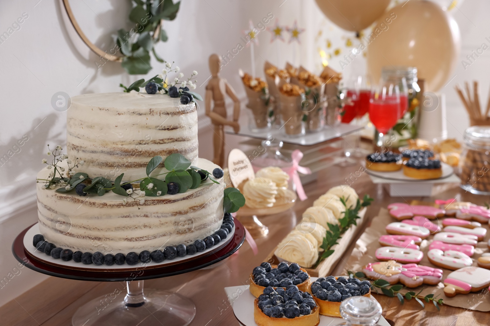 Photo of Baby shower party. Different delicious treats on wooden table indoors