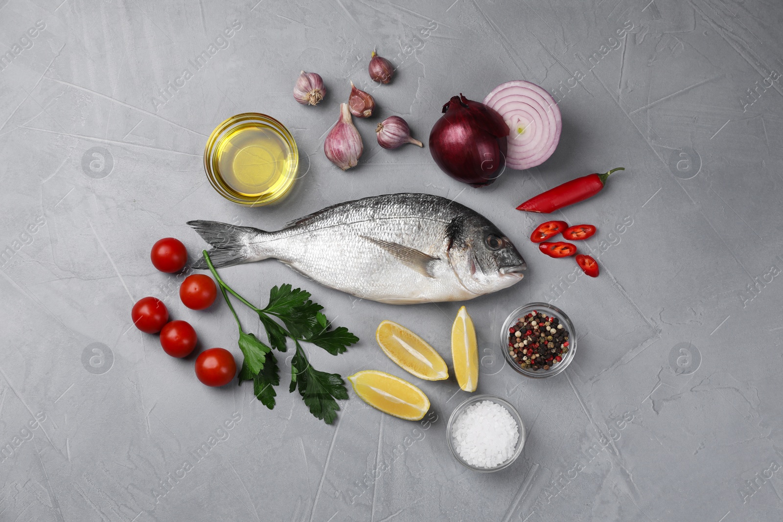 Photo of Flat lay composition with raw dorado fish and vegetables on grey table