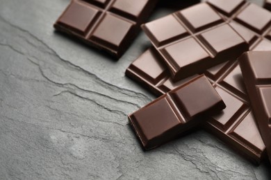 Photo of Delicious dark chocolate on black table, closeup. Space for text