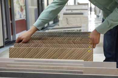 Man choosing tile among different samples in store, closeup