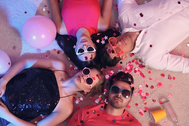 Group of friends lying on messy floor after party, top view