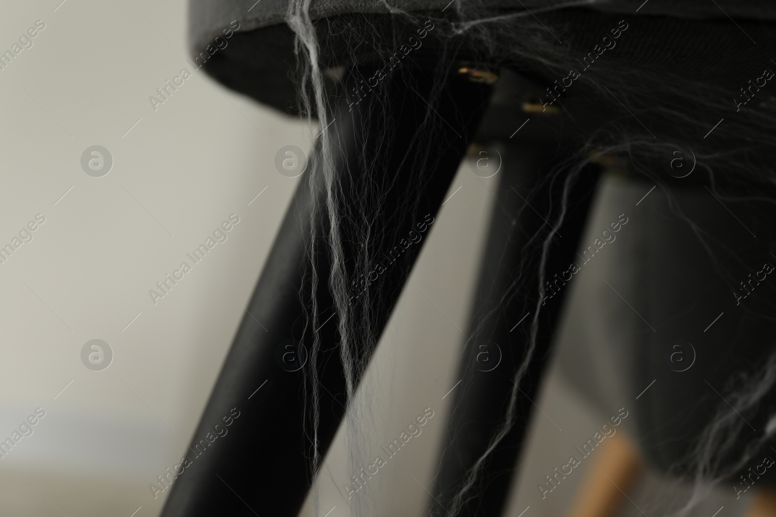 Photo of Old cobweb on chair in room, closeup