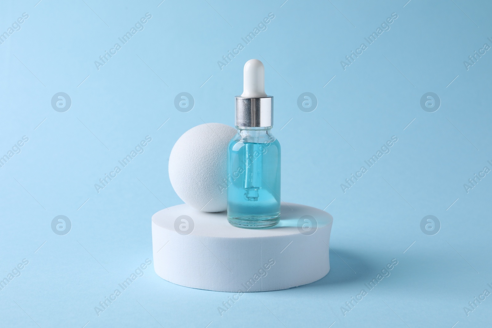 Photo of Presentation of bottle with cosmetic serum on light blue background