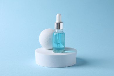 Presentation of bottle with cosmetic serum on light blue background