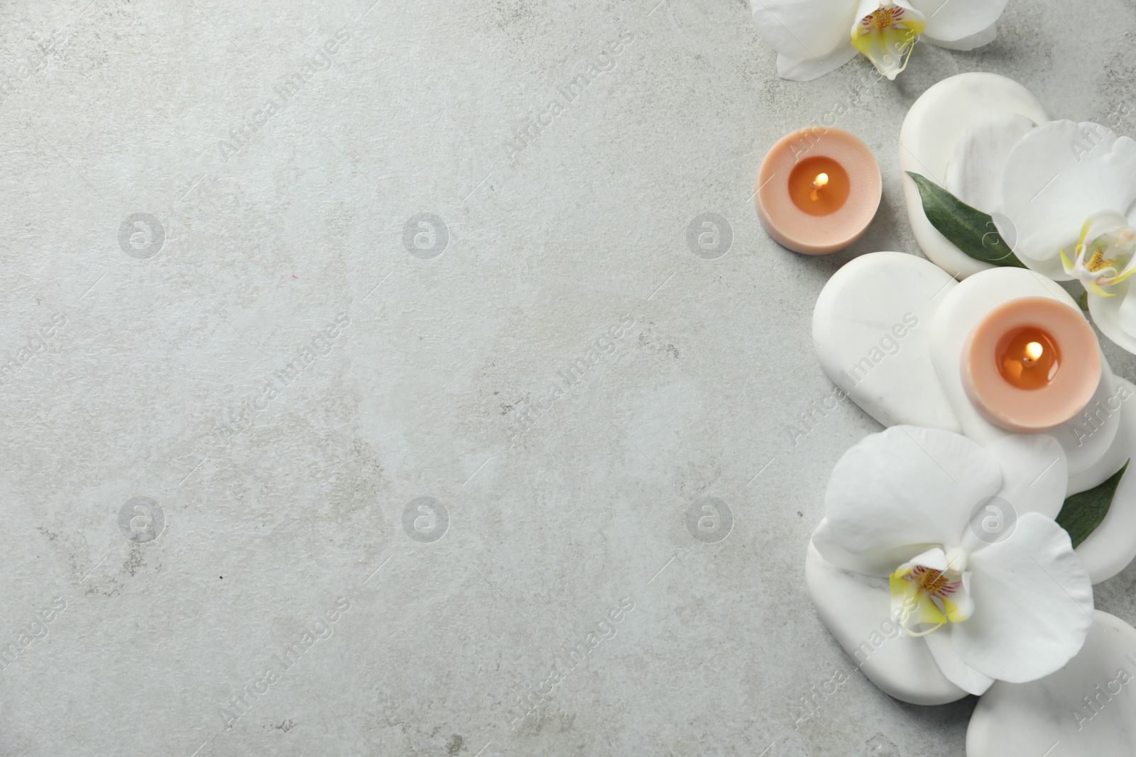 Photo of Flat lay composition with burning candles and spa stones on light grey table. Space for text