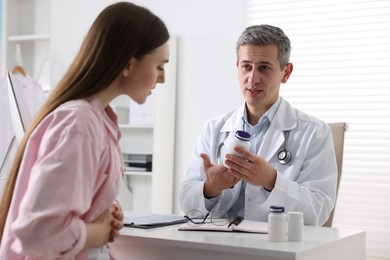 Photo of Gastroenterologist with pills consulting patient at table in clinic