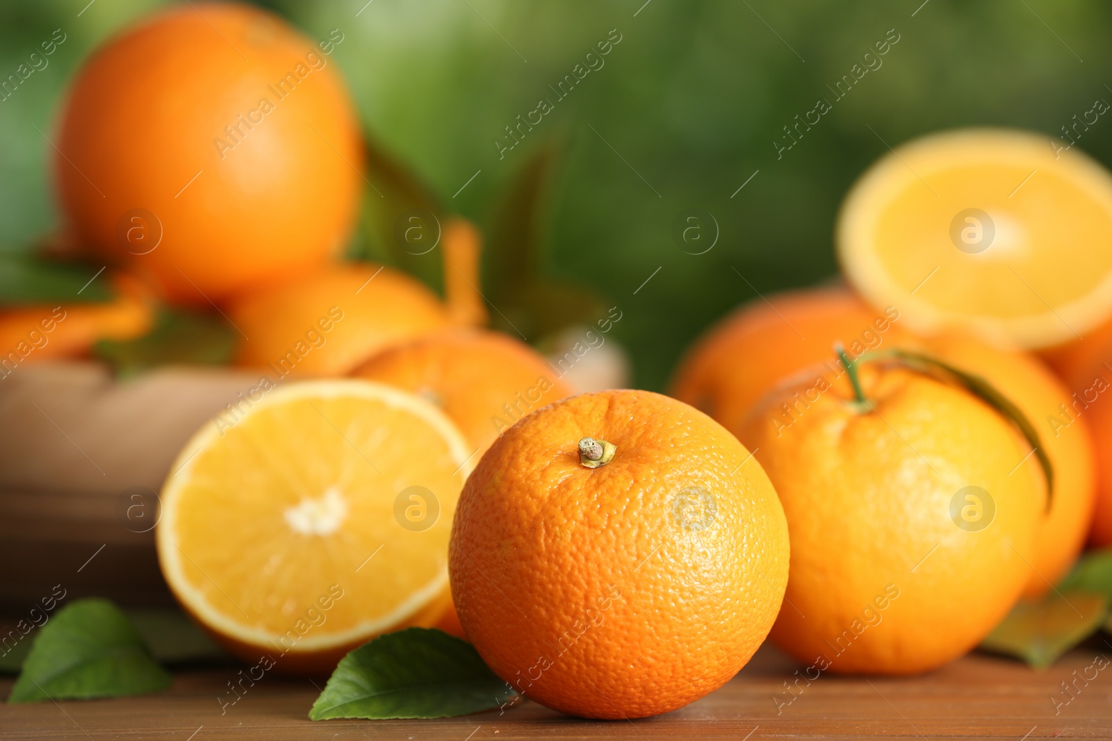 Photo of Fresh ripe oranges on wooden table against blurred background. Space for text