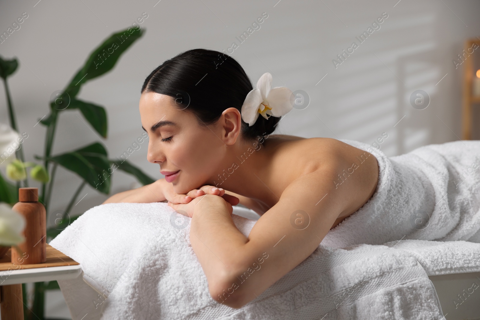 Photo of Beautiful woman relaxing on massage table in spa salon