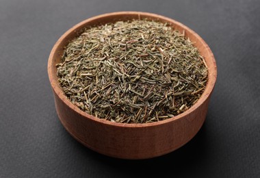 Photo of Wooden bowl with dried thyme on grey background