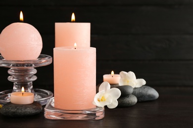 Composition of burning candles, spa stones and flowers on table. Space for text