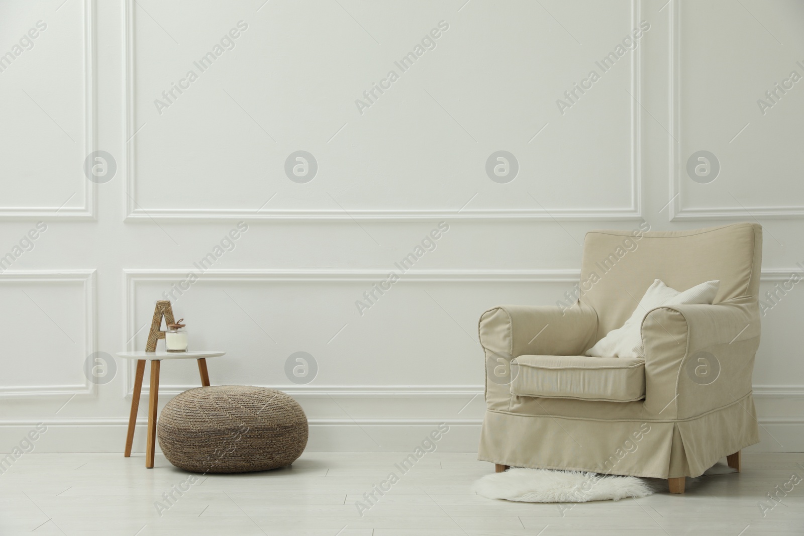 Photo of Stylish room interior with pouf, armchair and decor elements. Space for text