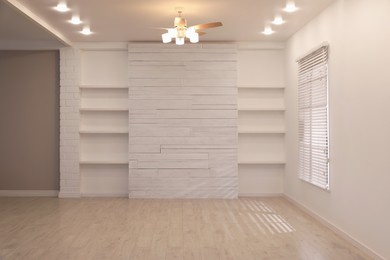 Empty room with textured wall, stylish wooden shelves and large window