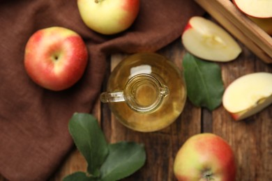Photo of Natural apple vinegar and fresh fruits on wooden table, flat lay