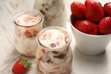 Photo of Tasty yoghurt with jam and strawberries on white marble board, closeup