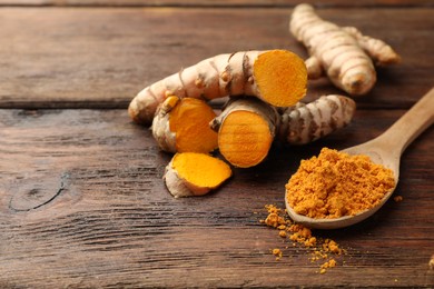 Aromatic turmeric powder and cut roots on wooden table. Space for text