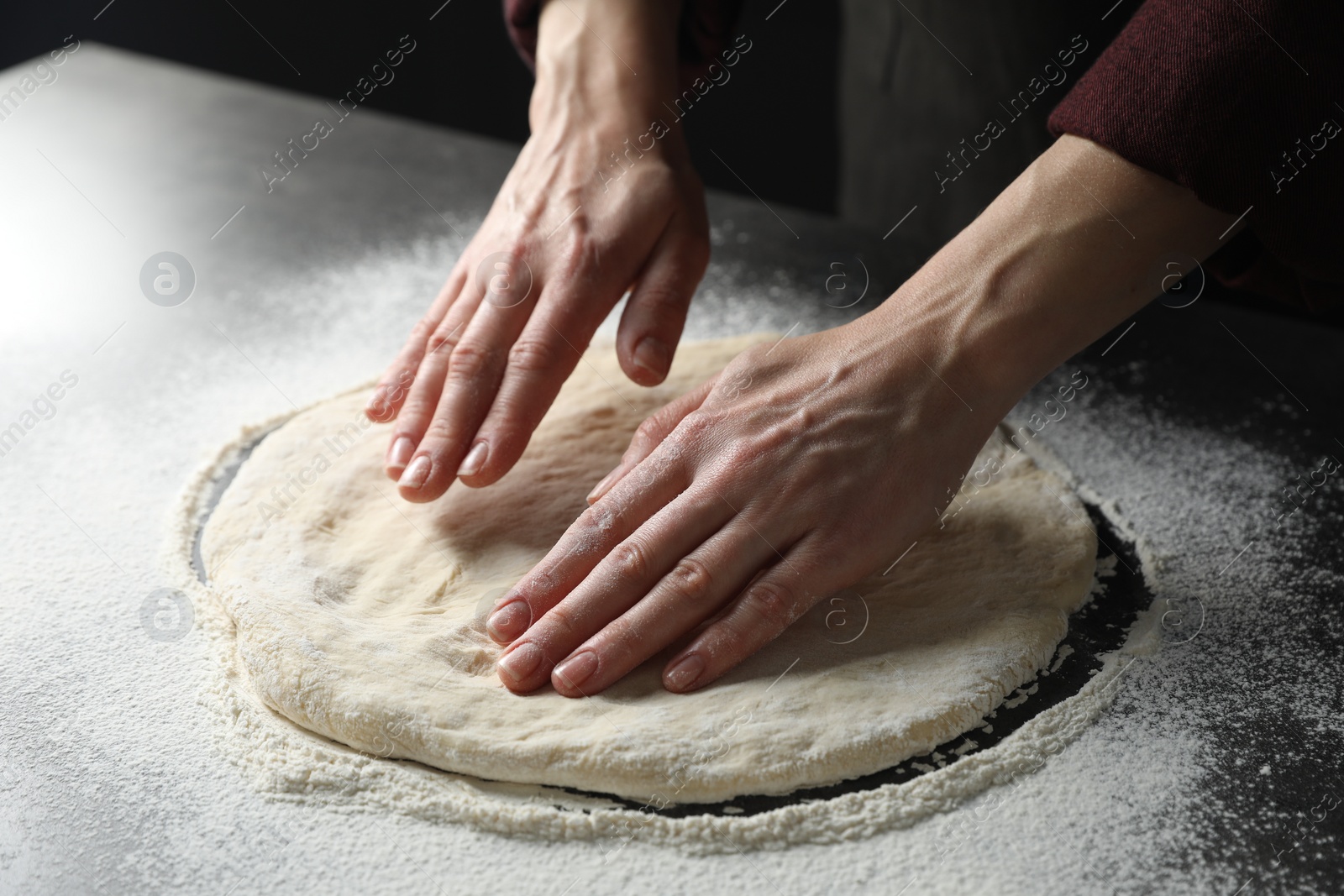 Photo of Woman kneading pizza dough at table, closeup