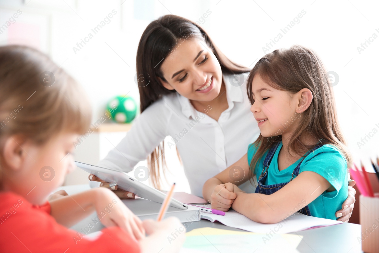 Photo of Female teacher helping girl with her task in classroom at school