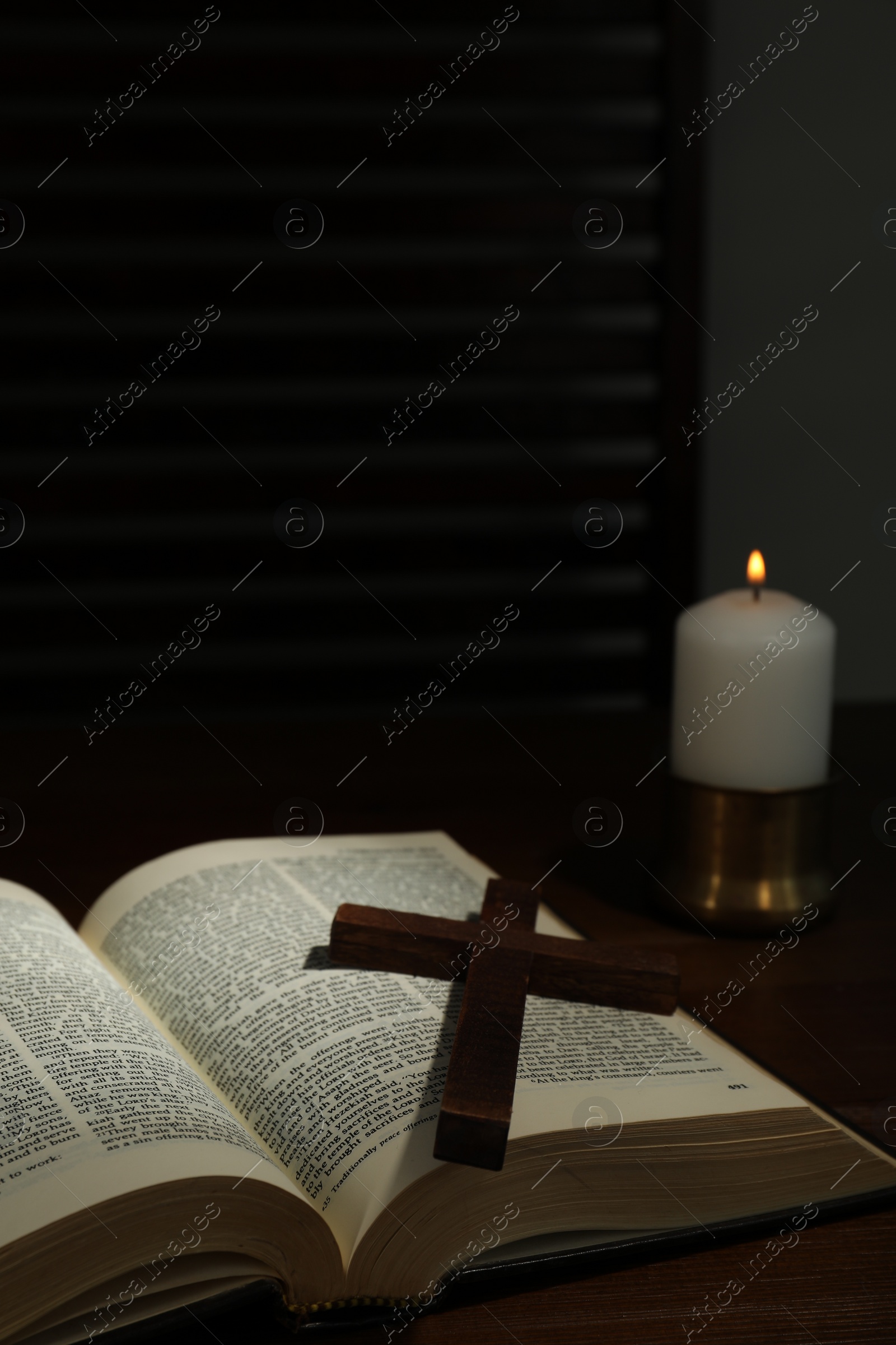 Photo of Cross, Bible and church candle on wooden table, space for text