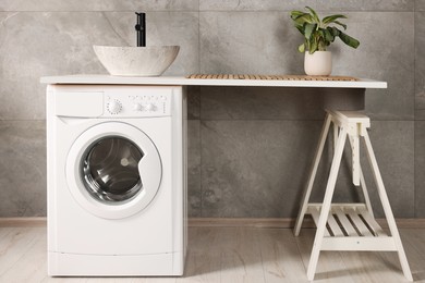 Photo of Stylish laundry room with modern washing machine. Interior design